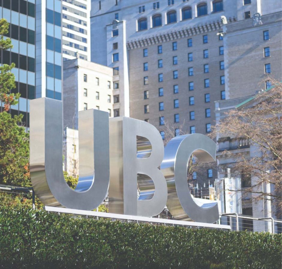 Three dimensional metallic 'UBC' sign set amongst a dense array of buildings